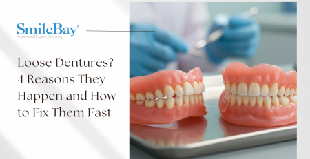 Full upper and lower dentures displayed on a metal tray with a gloved dentist in the background, representing issues like loose-fitting dentures and how SmileBay Dental in Penang can help.