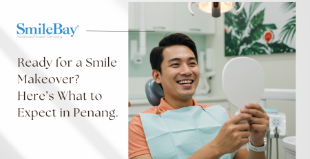 Smiling male patient looking into a mirror after smile makeover consultation at SmileBay Dental Penang